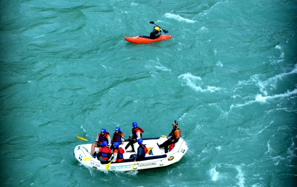 Rafting team with a safety kayaker on the turquoise Ganga in Rishikesh