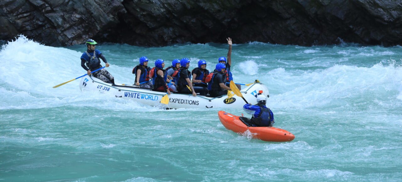 Safety kayaker escorting a raft through white water on the Ganga expedition