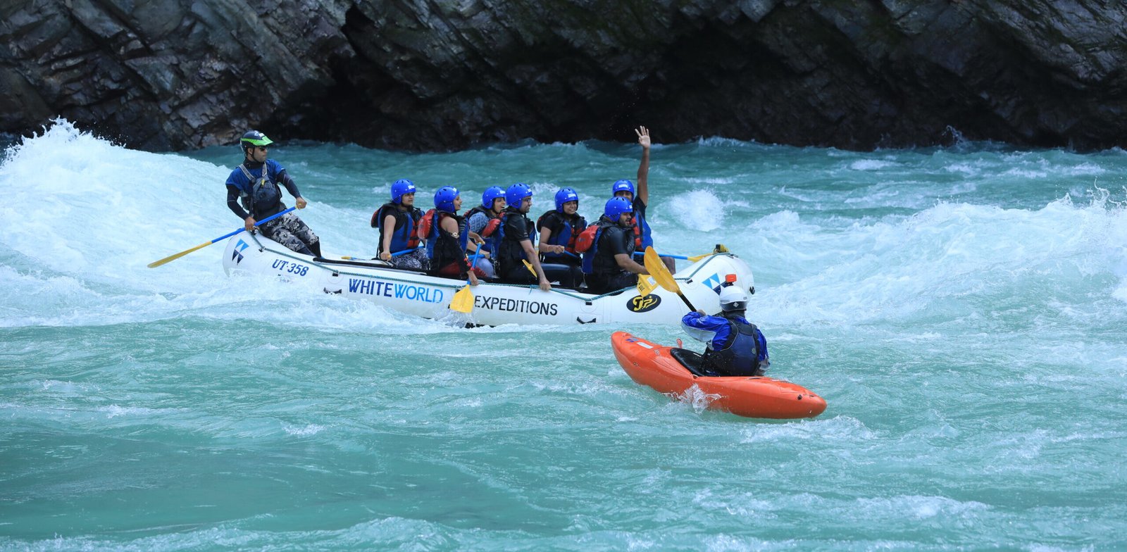 Safety kayaker escorting a raft through white water on the Ganga expedition